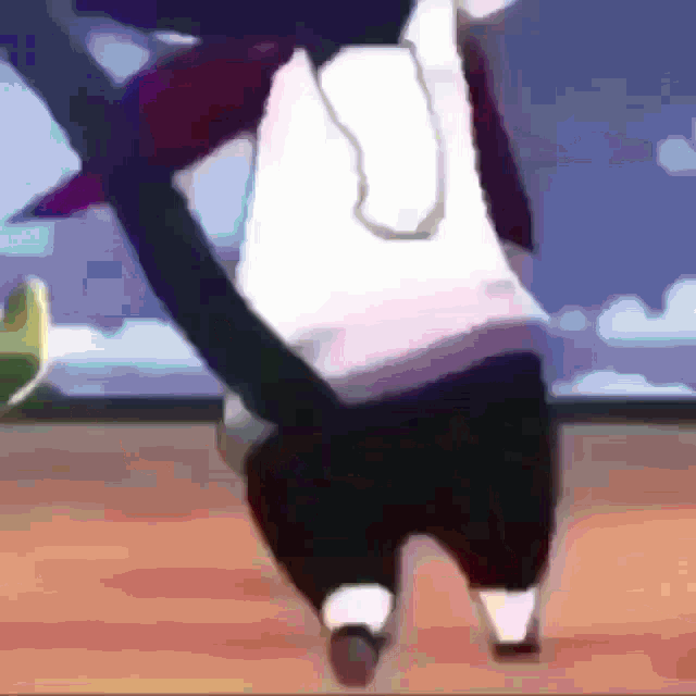a person in a white shirt and black shorts is walking on a wooden floor