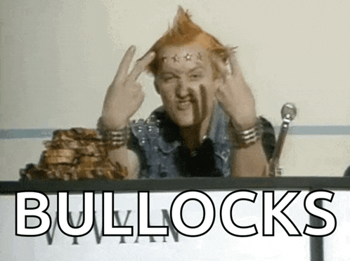 a man with a mohawk is giving the middle finger while sitting at a desk .