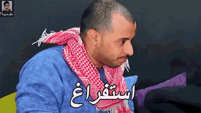 a man wearing a blue shirt and a red and white scarf has arabic writing on his neck