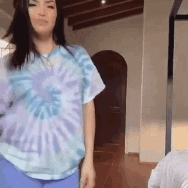 a woman in a tie dye shirt is standing in a living room .