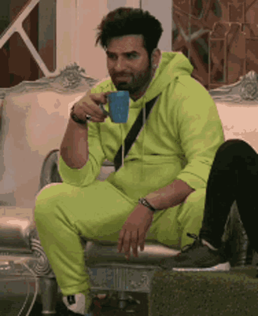 a man is sitting on a couch drinking a cup of coffee