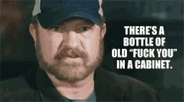 a man with a beard is wearing a baseball cap and says there 's a bottle of old fuck you in a cabinet