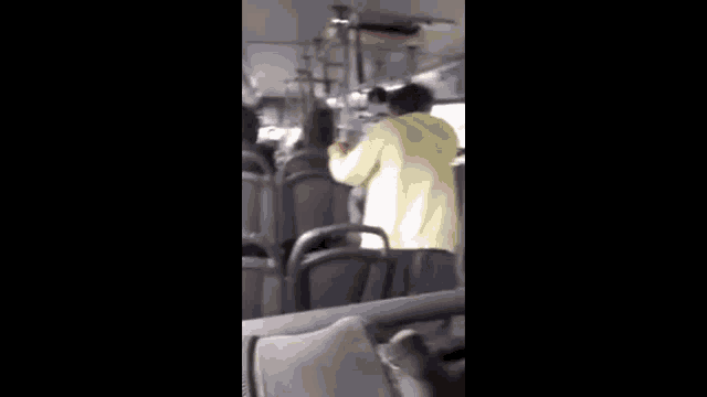 a man in a yellow hoodie is standing on a bus