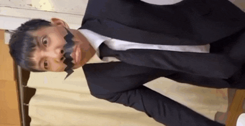 a man in a suit and tie with duct tape on his face is making a funny face .