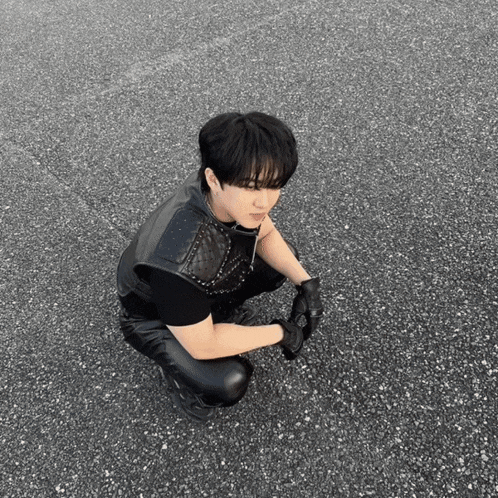a man in a leather vest and gloves is squatting down