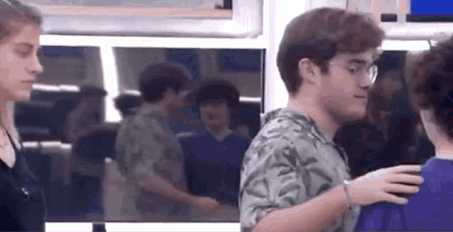 a man is hugging another man in a room while a woman looks on .