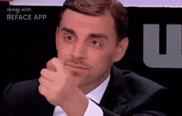 a man in a suit and white shirt is making a funny face with his hand