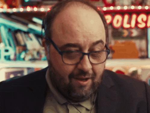 a bald man with glasses and a beard is standing in front of a sign that says polis