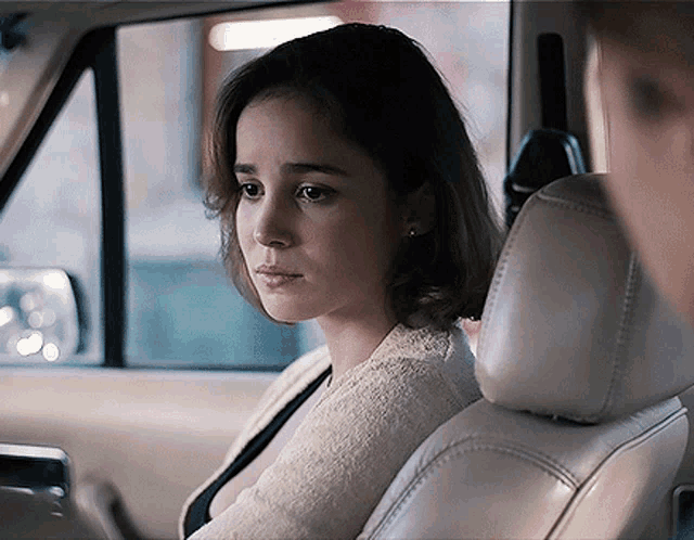 a woman is sitting in a car looking out the window