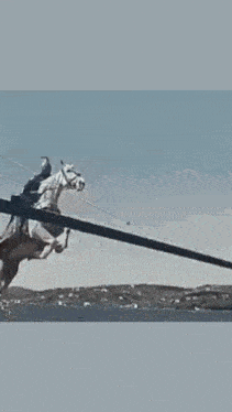 a man in a helmet is riding a white horse