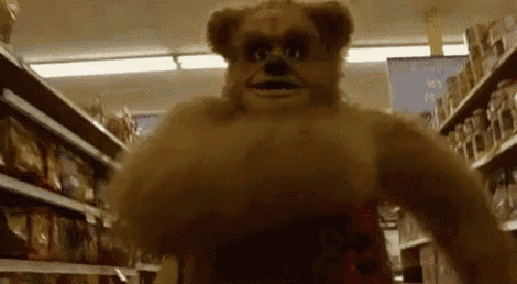 a teddy bear is walking down the aisle of a store .