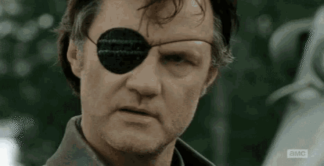 a man with a patch on his eye is making a funny face .