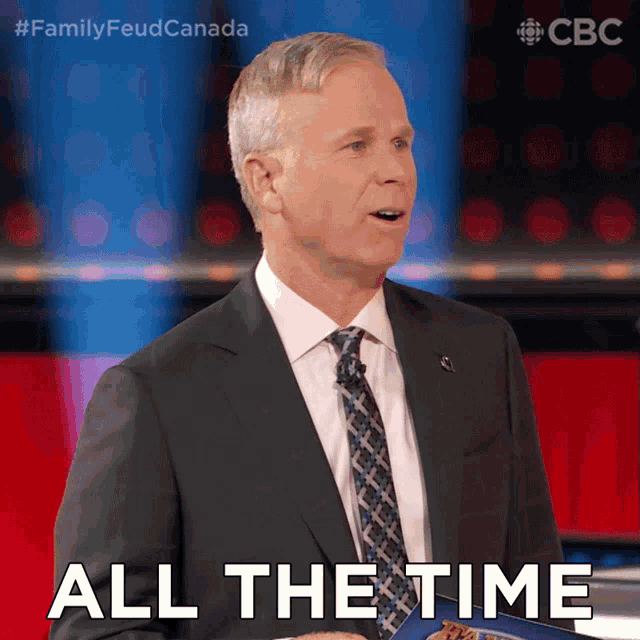 a man in a suit and tie says " all the time " while holding a book