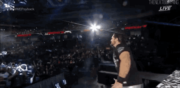 a man in a black shirt is standing in front of a crowd at a wrestling show