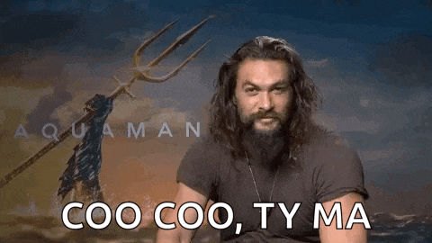 a man with long hair and a beard is pointing at the camera .