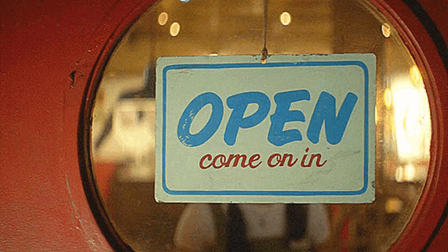 an open sign hangs in a round window