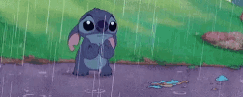 stitch from disney 's lilo and stitch is standing in the rain with a sad look on his face .