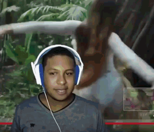 a young man wearing headphones looks at the camera with a woman in the background