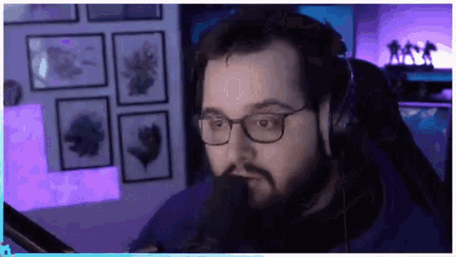 a man with glasses and a beard is wearing headphones in front of a microphone