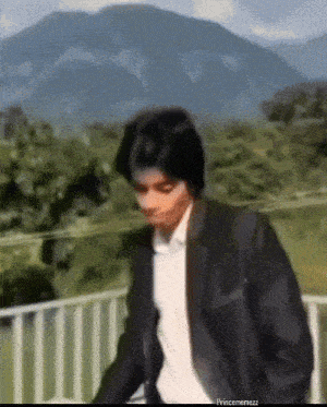 a man in a suit is standing on a balcony with mountains in the background and the caption princememezz