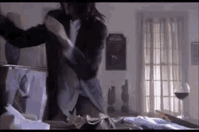 a man in a suit is standing next to a woman in a bedroom .
