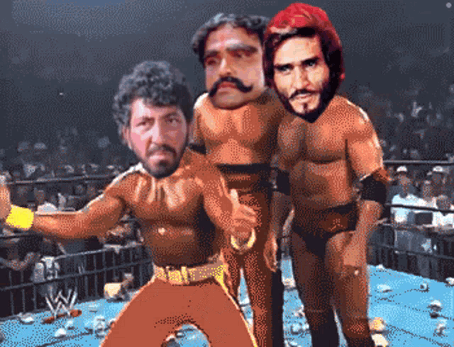 three wrestlers are standing in a ring with a w logo on the bottom right