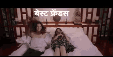 two women are sitting on a bed with their legs crossed and their hair is flying in the air .