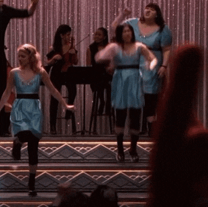 a group of women are dancing on a stage in front of a curtain