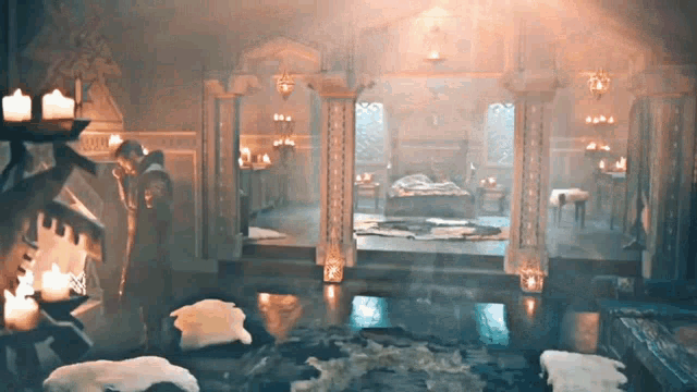 a man is standing in front of a fireplace in a room with a bed and candles .