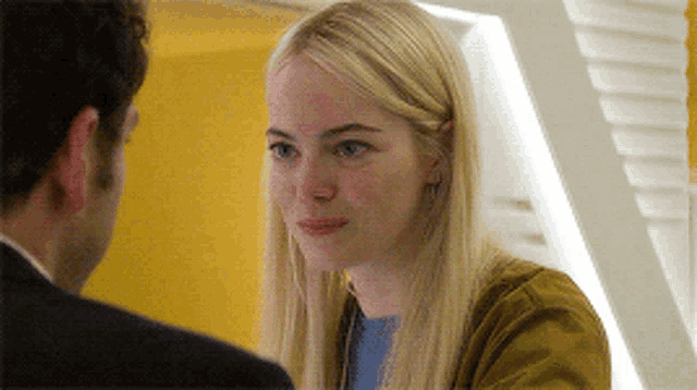 a woman in a yellow jacket looks at a man in a suit