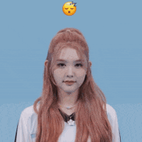 a girl with long red hair is holding her hands up in front of a blue background