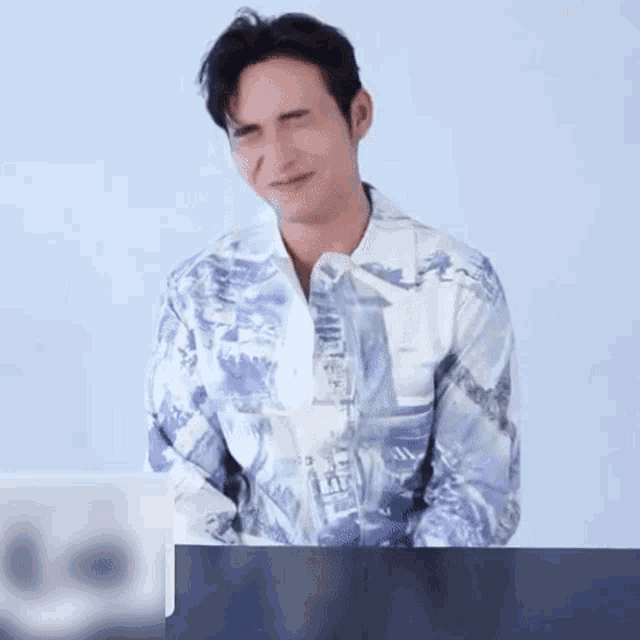 a man in a blue and white shirt is sitting at a table with a glass of water .