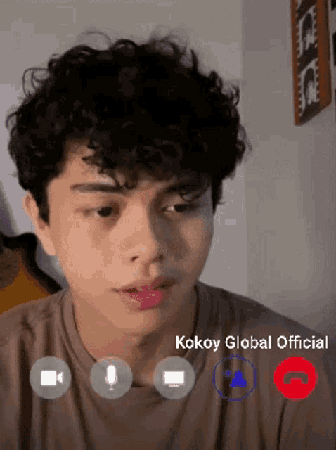 a young man with curly hair is talking on a video call with kokoy global official