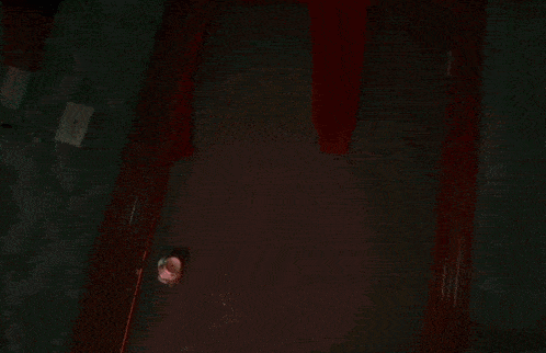 a person is holding a knife in front of a door in a room with red smoke coming out of it .