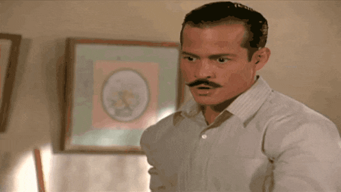 a man with a mustache is standing in front of a picture