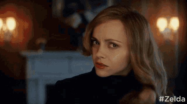 a woman with blonde hair and red lipstick is wearing a black turtleneck sweater .
