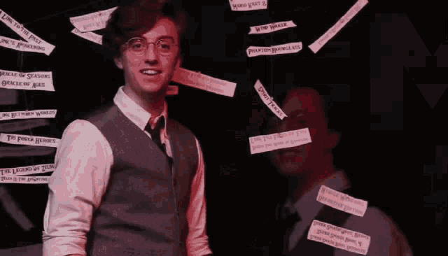 two men are standing next to each other in front of a wall with sticky notes on them .