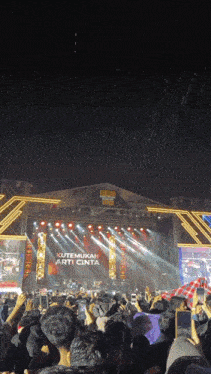 a crowd of people watching a concert with a stage that says " kutemukan arti cinta "