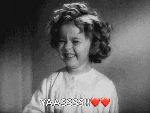 a little girl with curly hair is smiling and saying yaasss !