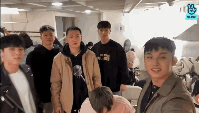 a group of young men are standing in a room and one of them is wearing a sweatshirt that says " made in korea " on it
