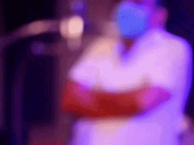 a blurry picture of a person standing in front of a microphone in a dark room .