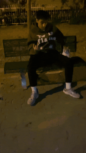 a man wearing a hoodie that says flakes on it sits on a bench with a cat