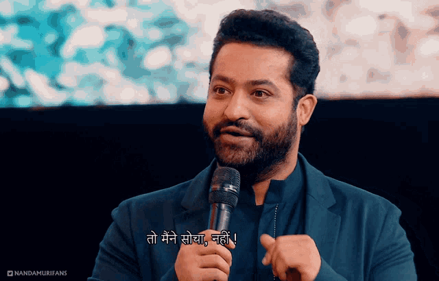 a man with a beard is holding a microphone and says " to me " in a foreign language