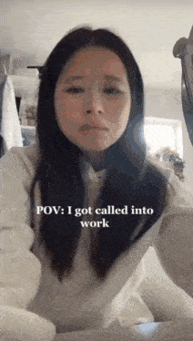 a woman is sitting at a table with the caption " pov : i got called into work "