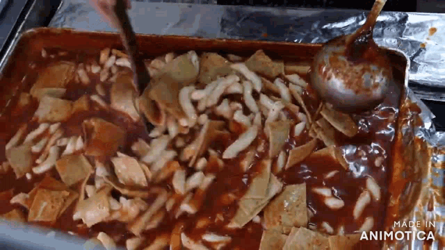 a tray of food is being stirred with a ladle and the words made in animatica can be seen in the corner