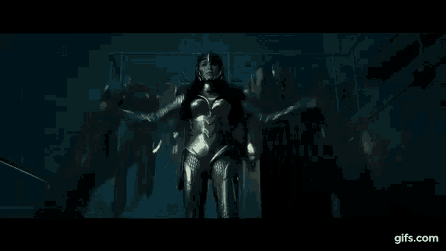 a woman in a gold costume is standing in a dark room with a fence in the background .