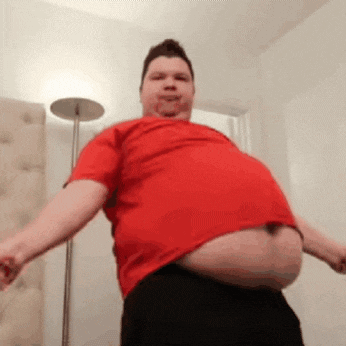 a man with a very large belly is wearing a red shirt and black pants .
