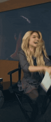 a woman with blonde hair is sitting in a chair laughing