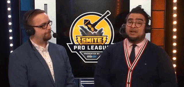 two men are standing in front of a smite pro league logo