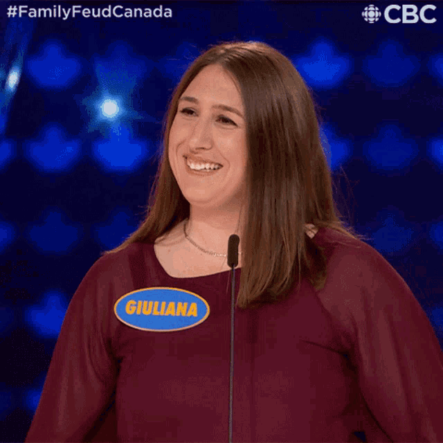 a woman stands in front of a microphone with a name tag that says giuliana